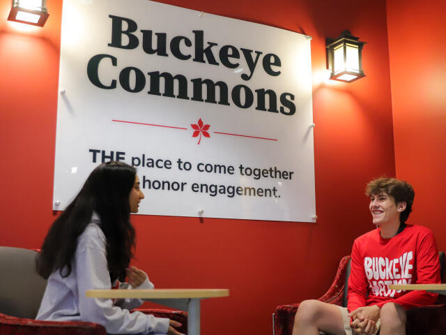 Two students talking beneath a sign that says "Buckeye Commons-THE place to come together
