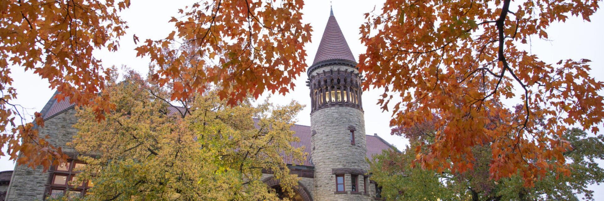 the tower of Orton Hall visible through trees with fall color leaves